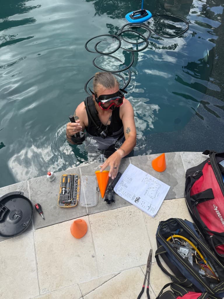 Diver with hydrophone and blueprints during pool leak detection