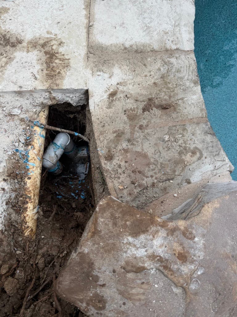 Deck excavation revealing underground plumbing at pool edge — Leander